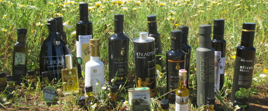 many bottles of Greek olive oil outside, in front of a field of daisies