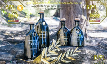 Four Pamako olive oil bottles in a forest, with logos and words about BIOL prizes they won