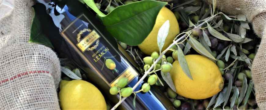 a bottle of Laconiko lemon infused olive oil, lying on its side in the midst of harvested olives and lemons