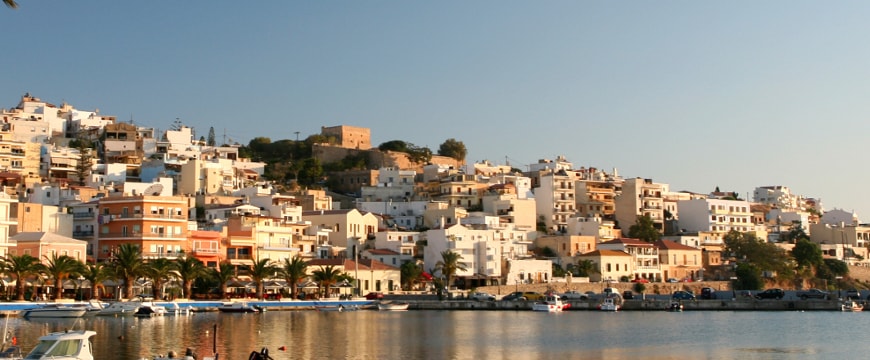 white and pastel-colored buildings on a hillside next to water