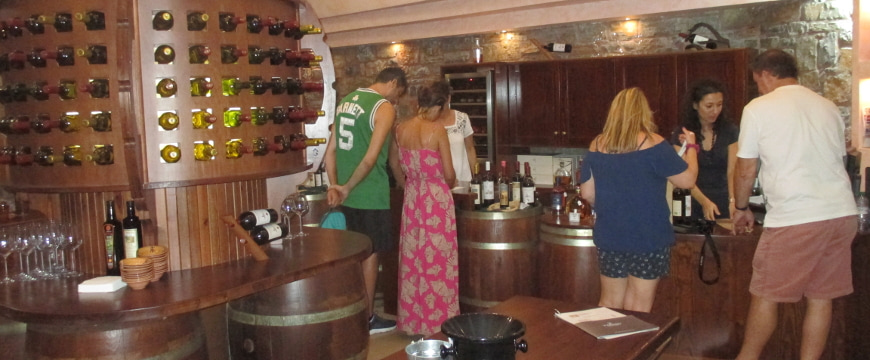 The Toplou wine tasting room, with bottles of wine on display and visitors talking with staff about wine choices