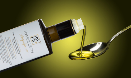 a bottle of Hypereleon extra virgin olive oil, with olive olive oil from it being poured into a spoon