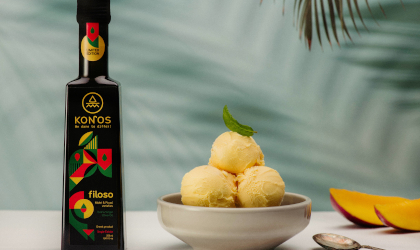 a black bottle of Konos Filoso EVOO with a brightly-colored label on the left, and a white bowl with three scoops of ice cream on the right, and palm leaf patterns in the background