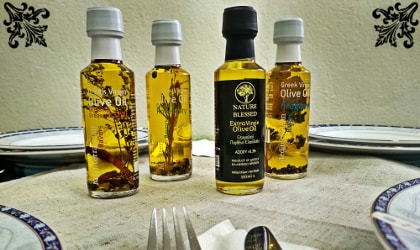 Four small bottles of Nature Blessed olive oil and flavored olive oil on a table