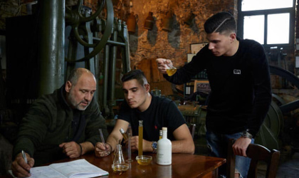 Kostas Protoulis and his two sons examining olive oil at a table