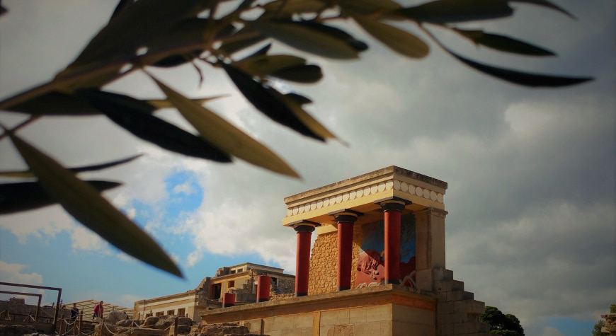 a colorful, reconstructed part of the Minoan Palace of Knossos, with an olive branch in the foreground