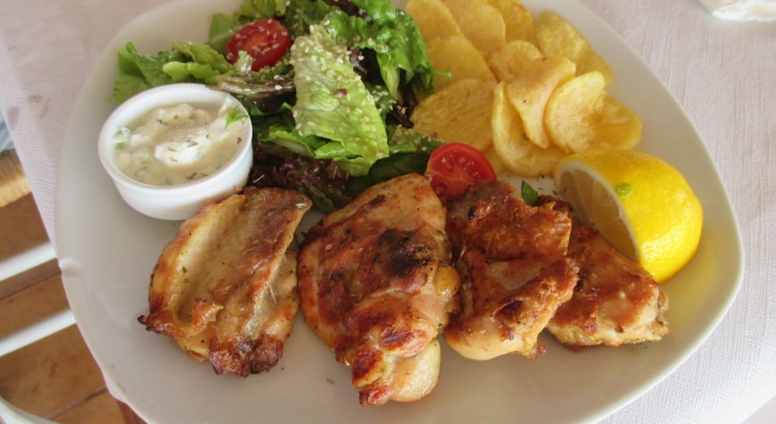 chicken thighs, fried potatoes, small salad, tzatziki, and lemon at Plateia Taverna