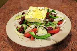 Greek salad with a large square of white feta cheese on top