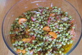 Peas with olive oil, carrots, onions, tomato sauce, etcetera in a glass bowl