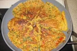 carrot onion parsley frittata in a frying pan