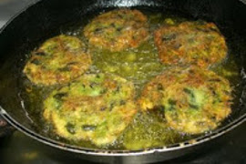 Zucchini patties frying in a cast iron skillet