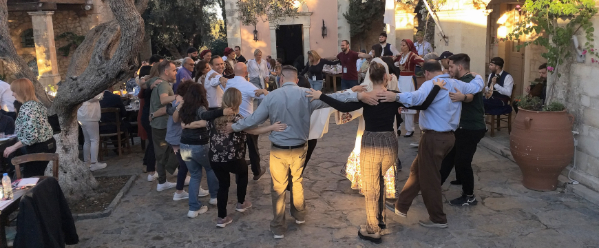 people in regular clothes and in costumes dancing in a village square in front of a church