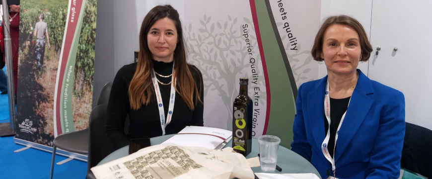 Two women sitting at a table at the Food Expo with a bag and papers related to the LIVINGAGRO project in front of them