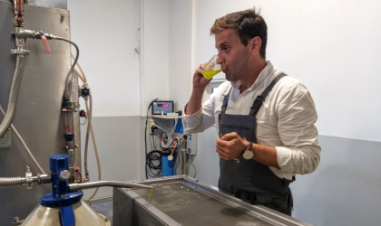 a young man drinking fresh olive oil in an olive mill