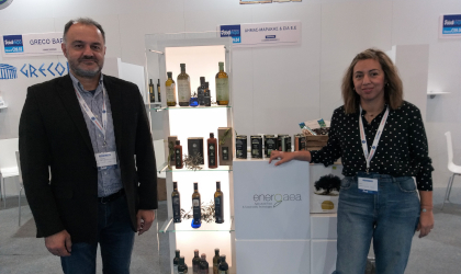 a man and a woman standing near an exhibit of Energaea olive oil bottles