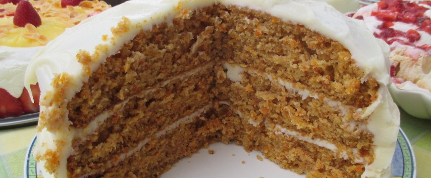 three layer carrot cake with cream cheese icing, with a big piece cut out
