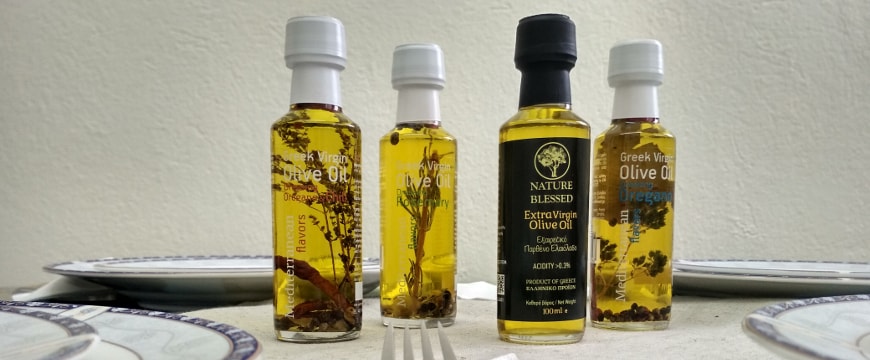 Four 100 milliliter bottles of Nature Blessed olive oil and flavored olive oil on a table