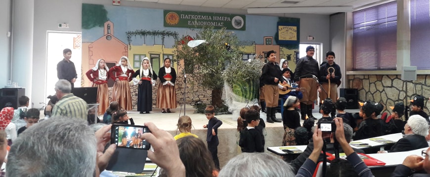 Costumed children onstage in front of an audience, with an olive tree in the center