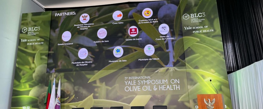 the backdrop for the stage at the Yale Symposium on Olive Oil and Health, showing sponsors with a background of olive branches