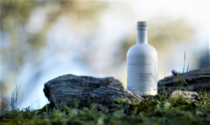 A white bottle of Aegea olive oil outdoors in a natural setting