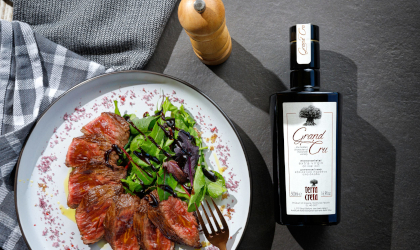 a bottle of Terra Creta Grand Cru olive oil next to a plate of food