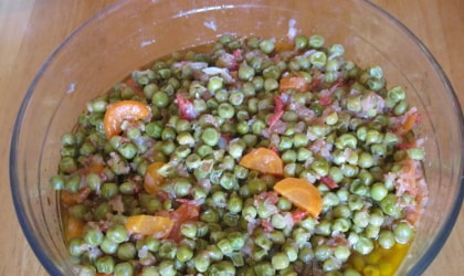 Peas with olive oil, carrots, onions etcetera in a glass bowl