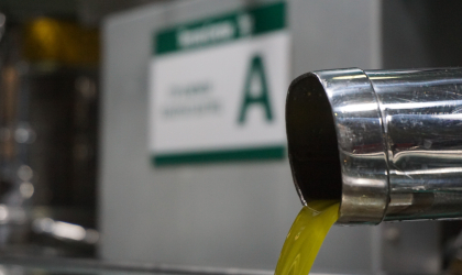 fresh olive oil pouring out of a stainless steel pipe in an olive mill