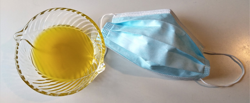 a disposable mask next to a small glass bowl of olive oil