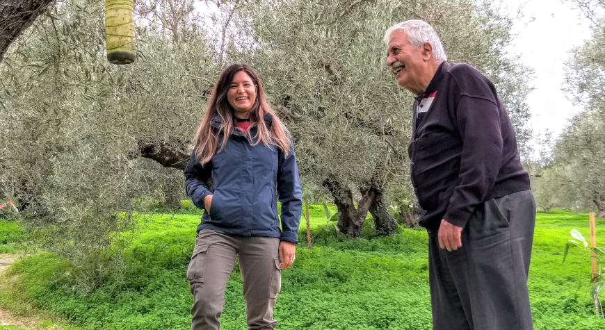 Eleftheria Mamidaki and Spiros Lionakis smiling about their discussion in an olive grove