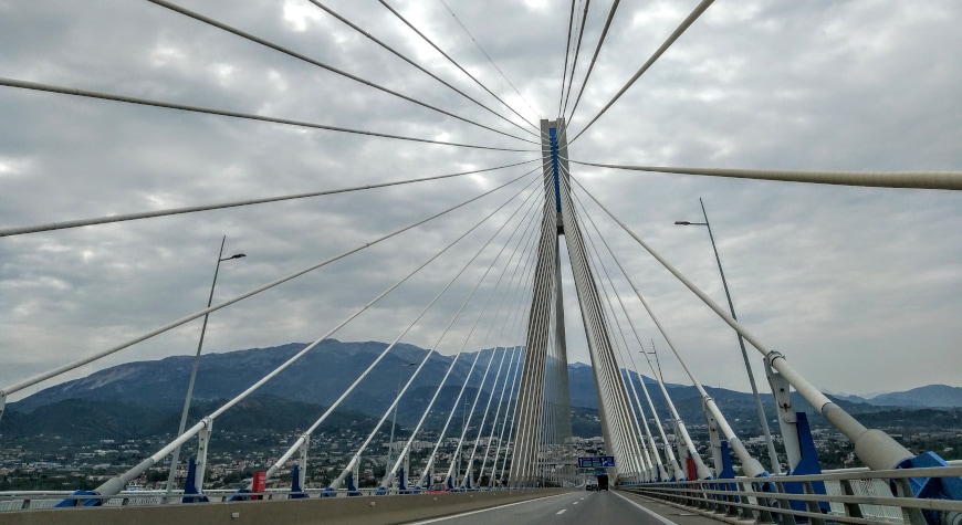 looking up at the cables of the Rio Antirrio bridge while crossing it, with mountains in the background