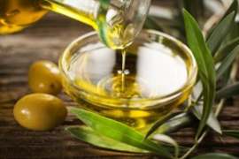 olive oil in a glass bowl, 2 olives to the left