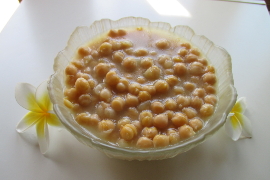 chickpeas in glass flower-shaped bowl, white and yellow plumeria flowers next to it