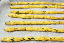 carrot parsley breadsticks lined up on a baking sheet